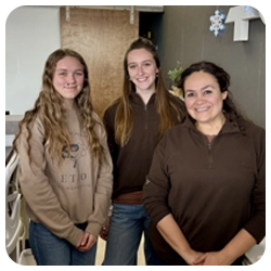 3 woman smiling behind the front desk.